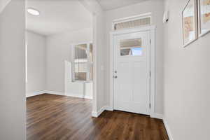 Foyer entrance featuring dark wood-type flooring and baseboards