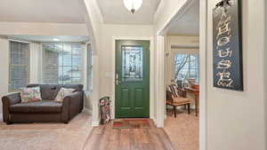 Foyer entrance with light wood-style flooring, a textured ceiling, and crown molding