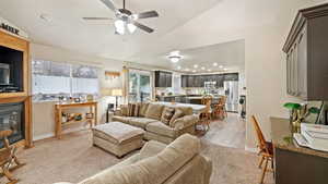 Living room featuring vaulted ceiling, a glass covered fireplace, ceiling fan, recessed lighting, and light carpet