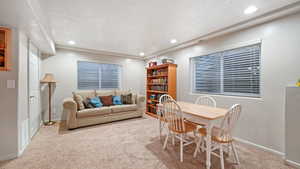 Dining room with recessed lighting, light colored carpet, and a textured ceiling
