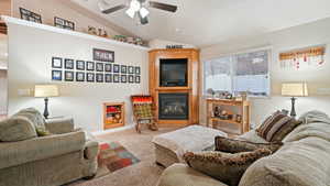 Living area featuring vaulted ceiling, a large fireplace, carpet, and a ceiling fan