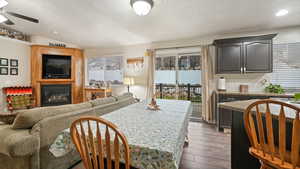 Dining room featuring dark wood-type flooring, a ceiling fan, vaulted ceiling, a large fireplace, and recessed lighting