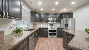 Kitchen featuring stainless steel appliances, recessed lighting, light stone counters, and light wood finished floors