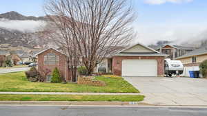 View of front of house featuring brick siding, concrete driveway, an attached garage, a front lawn, and a residential view