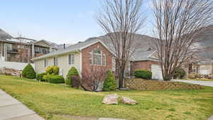 View of side of property with brick siding, a yard, and a garage