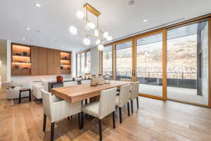 Dining area featuring expansive windows, light wood-type flooring, and a chandelier