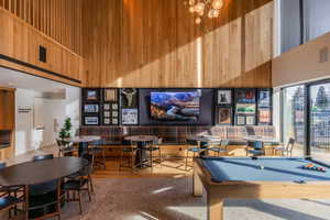 Playroom featuring a high ceiling, wood walls, billiards table, and hanging lights