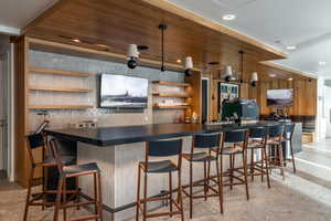 Bar area with open shelves, dark countertops, pendant lighting, and wooden walls