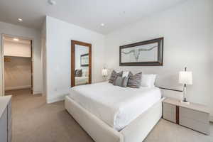Bedroom featuring a walk in closet, light colored carpet, and recessed lighting