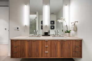 Bathroom featuring double vanity and a tile shower