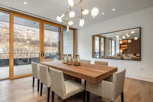 Dining area featuring light wood-style floors, floor to ceiling windows, and hanging lights