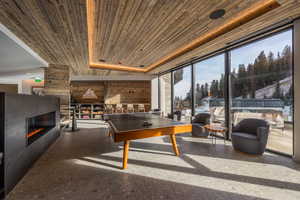 Game room with wooden ceiling and a glass covered fireplace