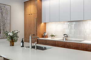 Kitchen featuring wood finish cabinetry, modern cabinets, tasteful backsplash, and black electric stovetop