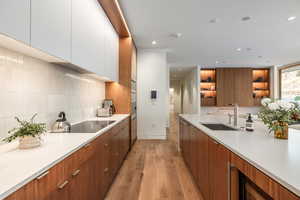 Kitchen with modern cabinets, light wood-style floors, dual tone cabinets, open shelves, and recessed lighting