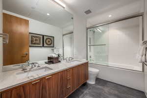 Full bathroom featuring double vanity, enclosed tub / shower combo, and recessed lighting