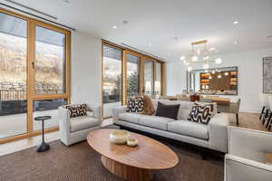 Living room with wood finished floors, hanging lights, and floor to ceiling windows