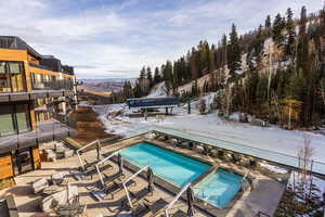 Snow covered pool featuring a patio area, a community pool, and a balcony