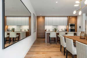 Dual tone kitchen featuring a kitchen bar, two tone color scheme, modern cabinets, light wood finished floors, and a large island
