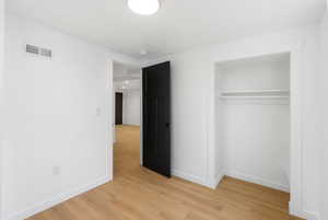 Unfurnished bedroom with light wood-type flooring and a closet