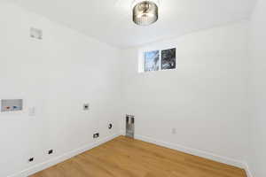 Laundry area featuring hookup for a washing machine, light wood-style flooring, electric dryer hookup, and a textured ceiling
