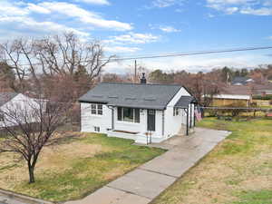 View of front of house with a chimney, a shingled roof, a front lawn, and stucco siding