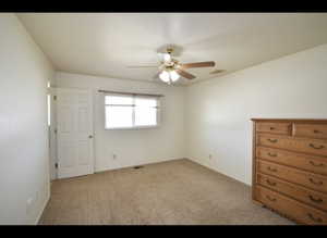 Primary bedroom with light carpet and ceiling fan