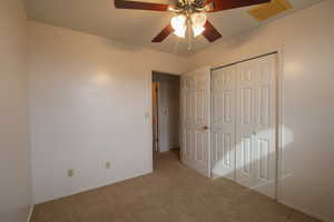 bedroom 1 featuring light colored carpet, ceiling fan, and a closet