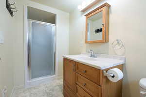 Basement Bathroom featuring a shower stall, vanity, and light tile patterned floors, in the bedroom