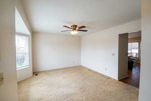 Carpeted empty room with a ceiling fan.