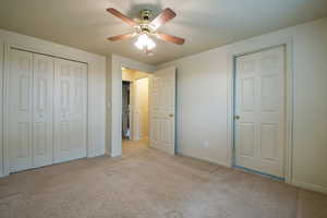 Bedroom 1 in the basement  featuring light carpet, ceiling fan, and a closet with a primary Bathroom