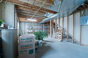 Unfinished basement with electric panel, washer and dryer hookups and the furnace.