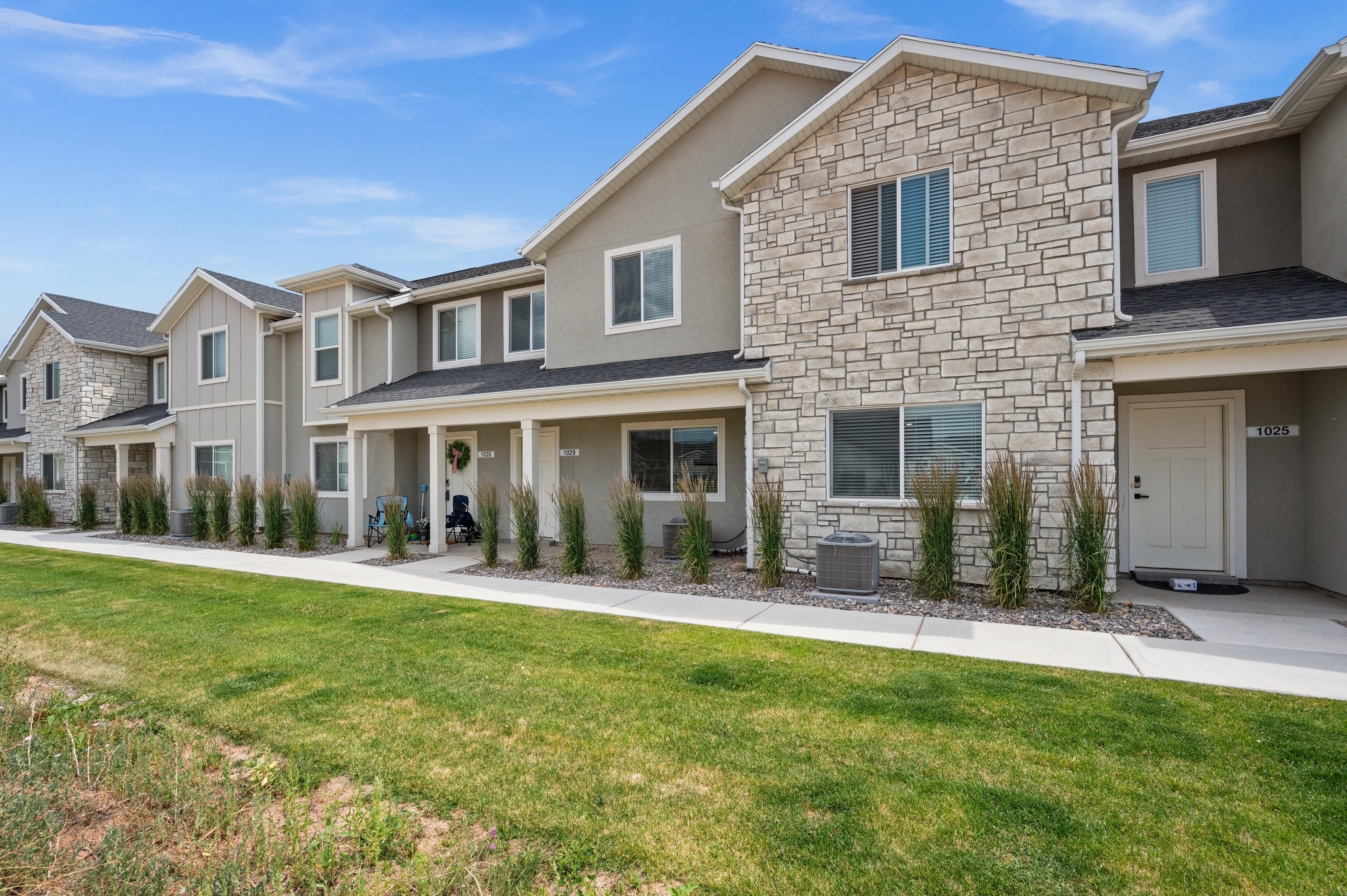 Townhome exterior featuring a stone facade and stucco finish