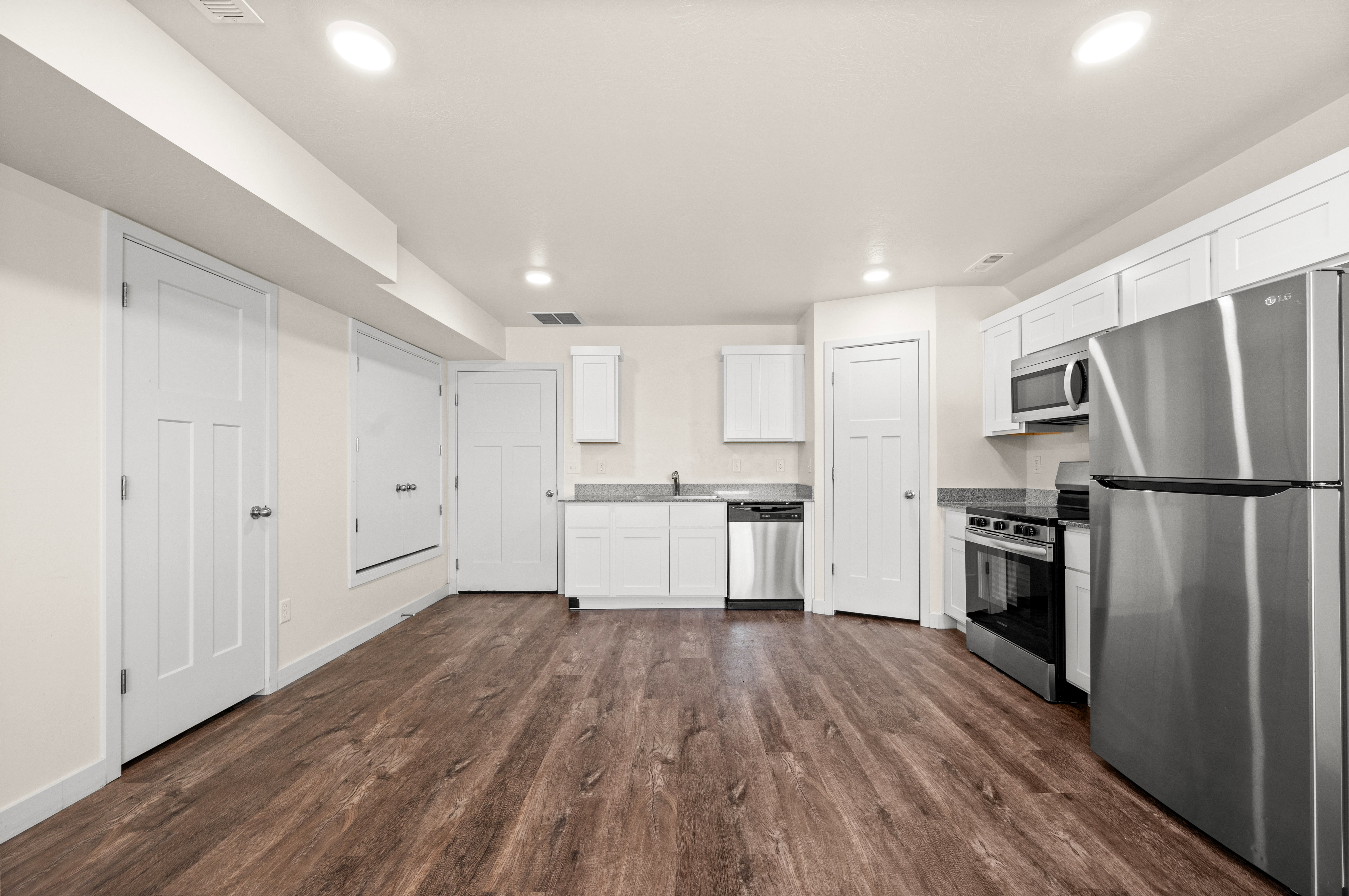 Kitchenette featuring wood-finish flooring, white cabinetry, stainless steel appliances, and recessed lighting