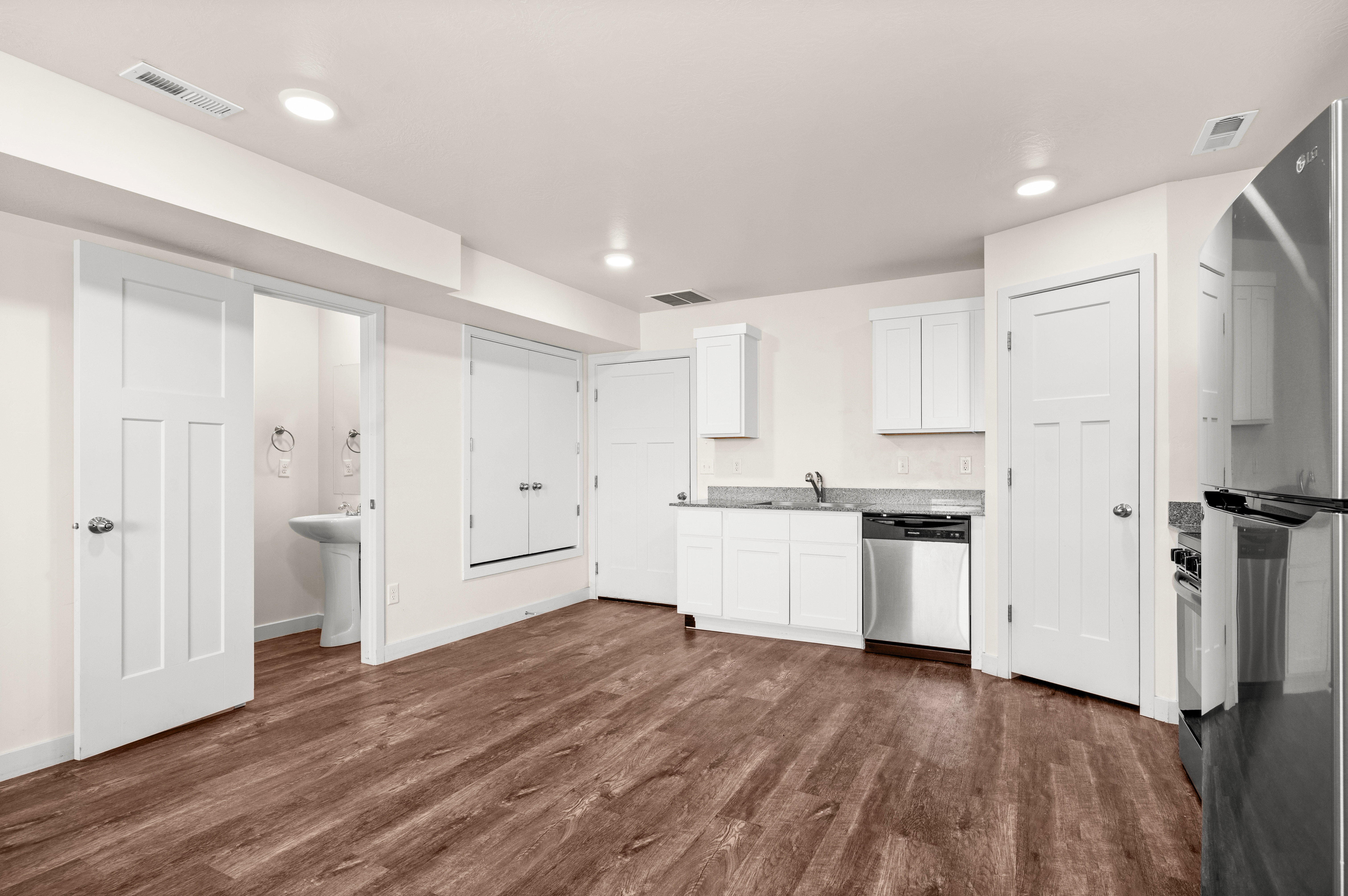 Open-concept space featuring wood-finish flooring, recessed lighting, and a compact kitchen