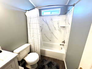 Bathroom with vanity, shower / bathtub combination with curtain, and dark wood-style flooring