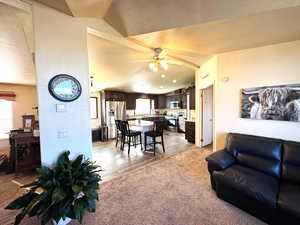 Living area featuring lofted ceiling, a ceiling fan, and light carpet