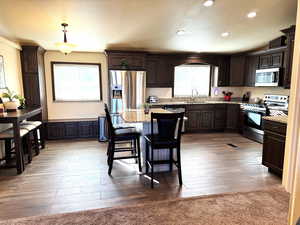 Kitchen featuring stainless steel appliances, dark wood finish cabinets, a kitchen breakfast bar, and a center island