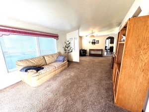 Living area featuring arched walkways and dark colored carpet