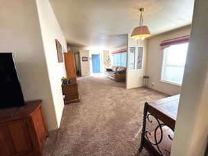 Dining area featuring carpet, a textured ceiling, a chandelier, and a textured wall