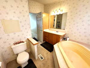 Bathroom with wallpapered walls, vanity, a garden tub, and light colored carpet