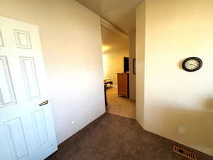 Hall with dark carpet and vaulted ceiling