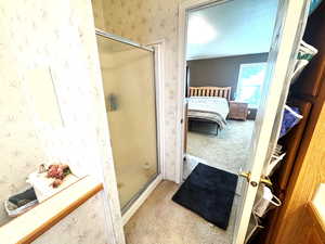 Bathroom featuring a stall shower, light colored carpet, ensuite bath, and wallpapered walls