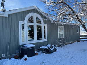 View of snow covered exterior featuring a cooling unit