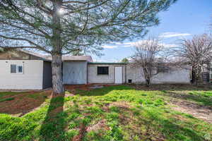 Rear view of property with concrete block siding, an outbuilding, and a lawn