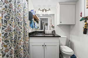 Full bath with curtained shower, vanity, and a textured ceiling