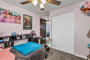 Bedroom with dark colored carpet, a closet, and ceiling fan