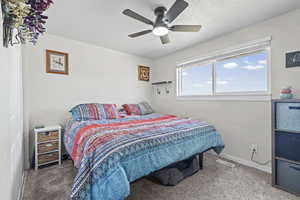 Bedroom with light colored carpet, ceiling fan, and a textured ceiling