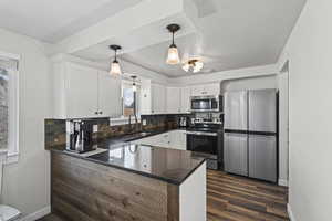 Kitchen featuring stainless steel appliances, dark stone countertops, decorative backsplash, pendant lighting, and white cabinets