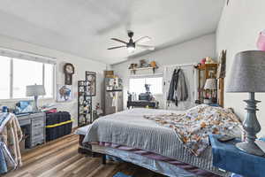 Bedroom with dark wood-style flooring, vaulted ceiling, ceiling fan, multiple windows, and a closet