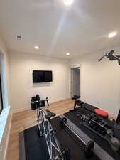 Workout area featuring light wood-style floors and recessed lighting